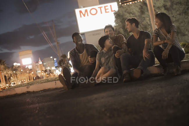 Menschen, die nachts auf dem Bürgersteig sitzen — Stockfoto