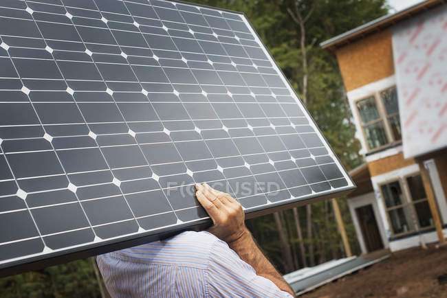 Workman carrying a large solar panel — Stock Photo