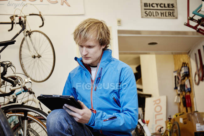Hombre que trabaja en una tienda de bicicletas - foto de stock