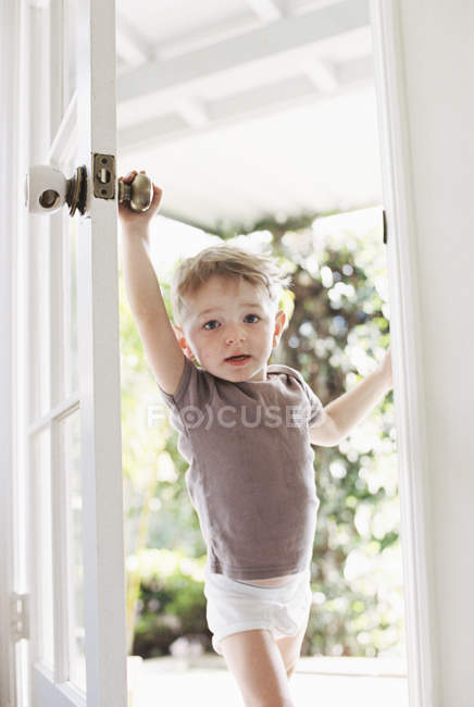 Kleiner Junge, der eine Tür öffnet. — Stockfoto