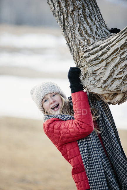 Chica joven agarrando un tronco de árbol . - foto de stock