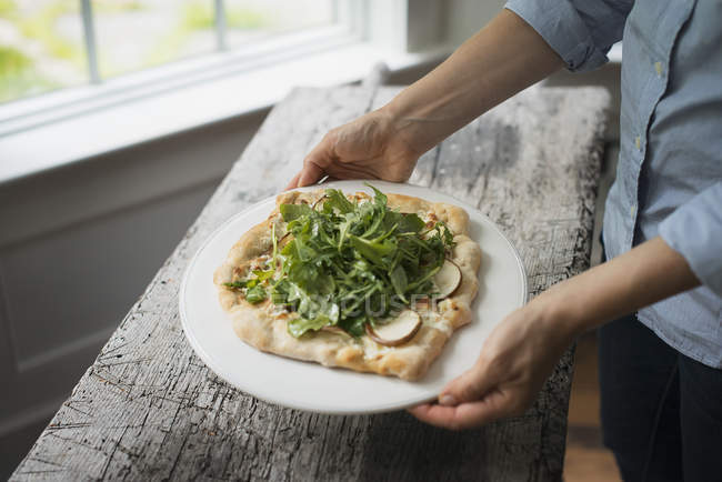 Person holding a plate with fresh salad — Stock Photo