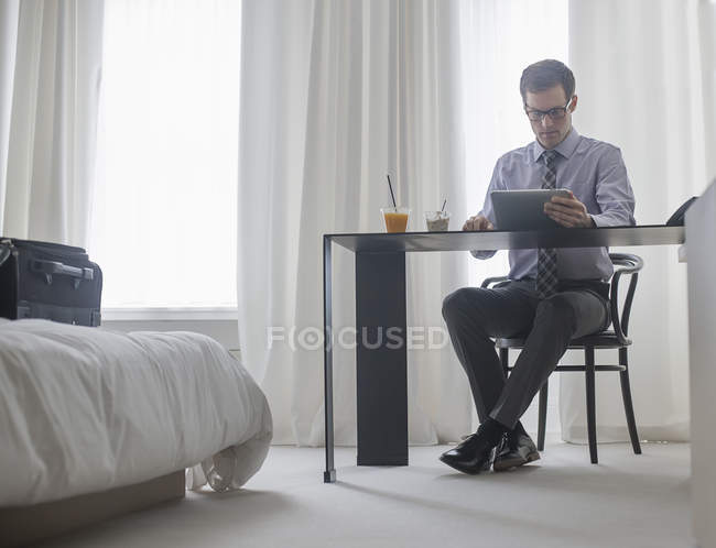 Uomo che lavora in una camera da letto d'albergo . — Foto stock