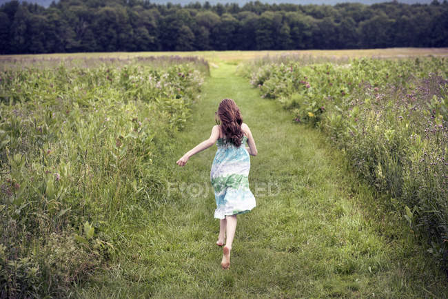 Fille courir à travers une prairie — Photo de stock