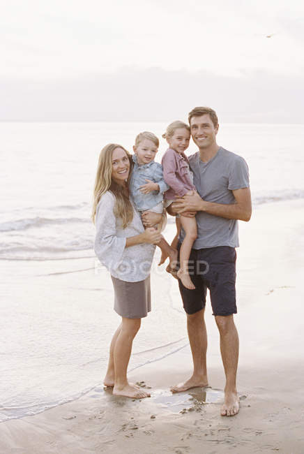 Familia en una playa de arena junto al océano - foto de stock
