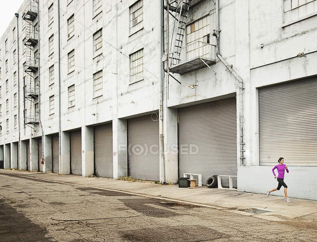 Donna che corre lungo una strada urbana — Foto stock