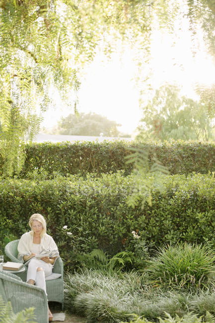 Donna seduta in un giardino — Foto stock