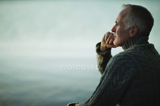 Mature man looking out over wate — Stock Photo