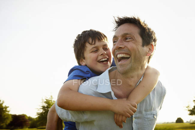 Padre dando a su hijo un lomo . - foto de stock