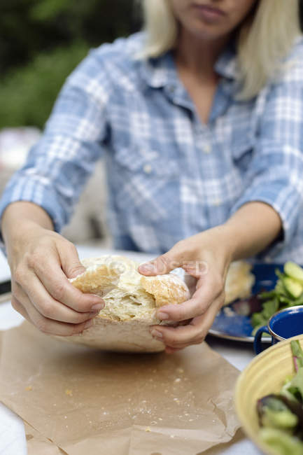 Woman tearing off a piece from a loaf — Stock Photo
