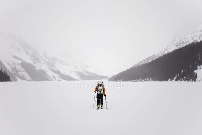 Лыжник, пересекающий замерзшее озеро — стоковое фото