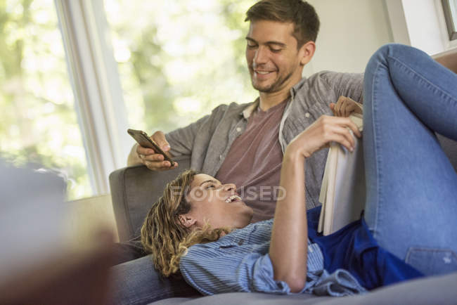 Man checking phone and a woman reading a book. — Stock Photo