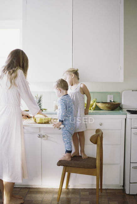 Femme avec des enfants debout dans une cuisine — Photo de stock