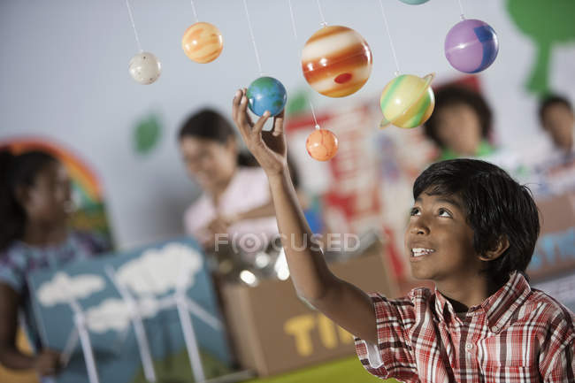 Niño mirando hacia arriba en una pantalla de los planetas - foto de stock