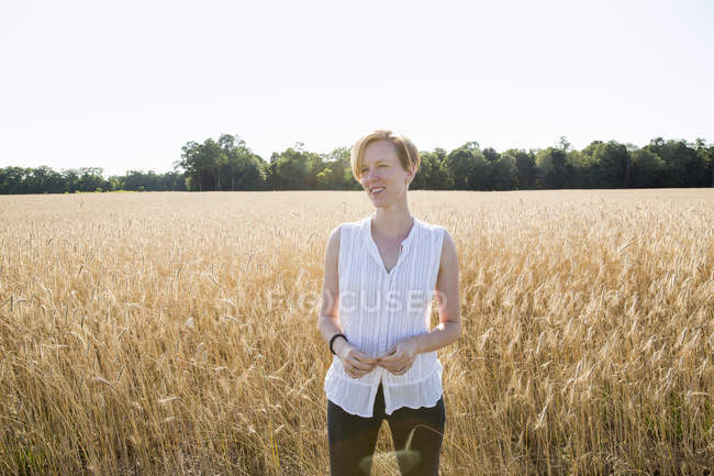 Junge Frau steht in einem Weizenfeld — Stockfoto