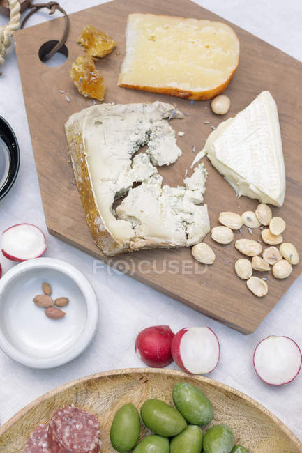 Tabla de quesos con aceitunas y frutos secos - foto de stock