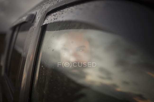 Hombre sentado en un coche mirando hacia fuera . - foto de stock