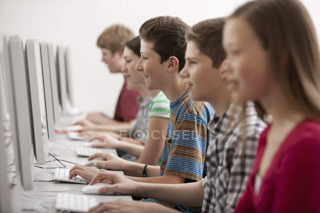 Estudiantes en una clase de computación trabajando en pantallas . - foto de stock