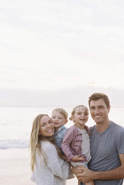 Familia en una playa de arena junto al océano - foto de stock