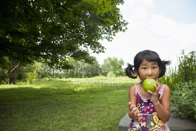 Kind kaut großen Apfel — Stockfoto