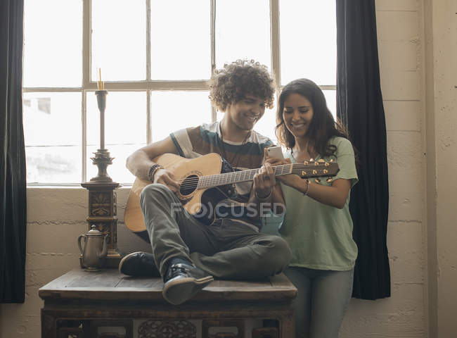 Homem tocando guitarra e uma mulher com telefone — Fotografia de Stock