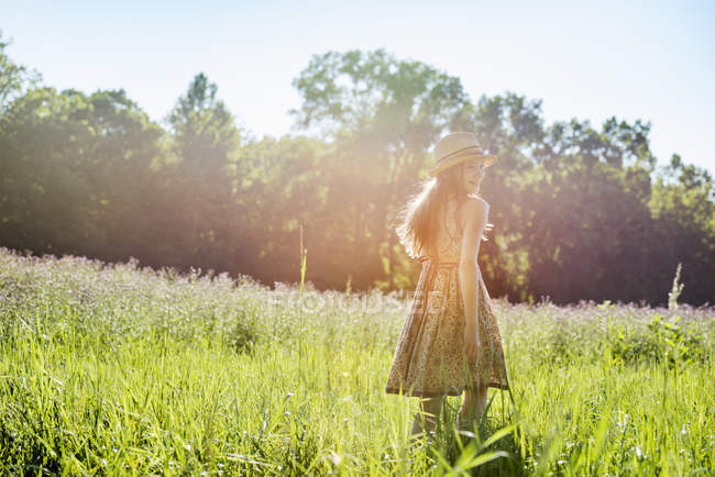 Chica caminando en un campo bajo el sol - foto de stock