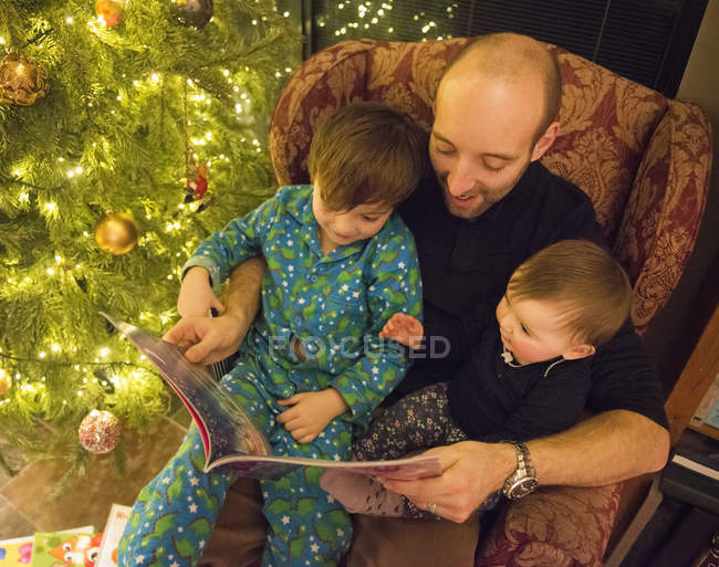 Man reading book to two children — Stock Photo