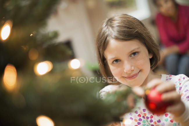 Girl placing bauble on Christmas tree — Stock Photo