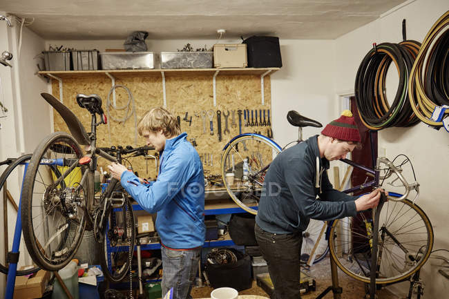 Hombres jóvenes reparando bicicletas - foto de stock