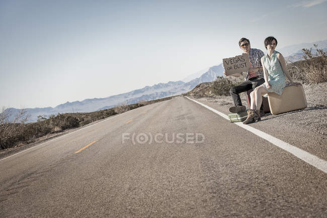 Casal na estrada no deserto hitchiking — Fotografia de Stock
