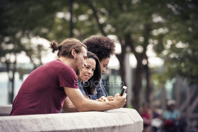 Homem e duas mulheres usando telefones inteligentes — Fotografia de Stock