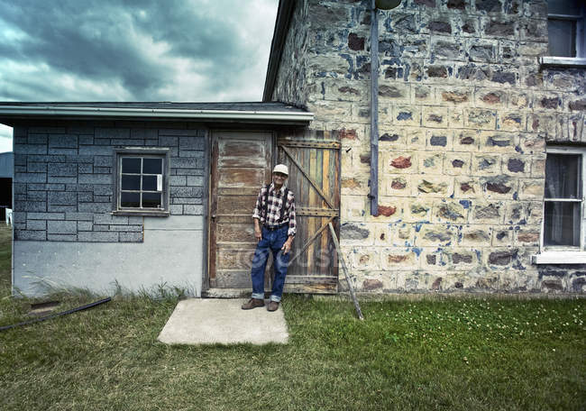 Farmer leaning against a doorjamb. — Stock Photo