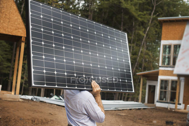 Trabalhador carregando um grande painel solar — Fotografia de Stock