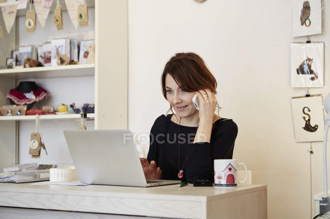 Mujer sentada en el escritorio y haciendo llamada - foto de stock