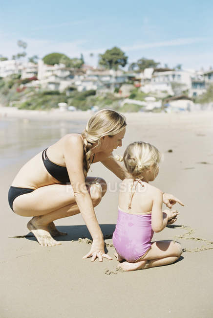 Femme en bikini jouant avec sa fille — Photo de stock