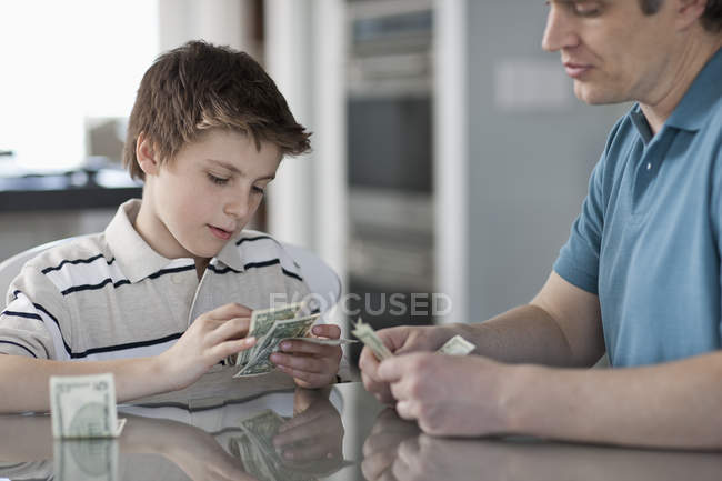 Мужчина и мальчик считают и обрабатывают наличные деньги . — стоковое фото