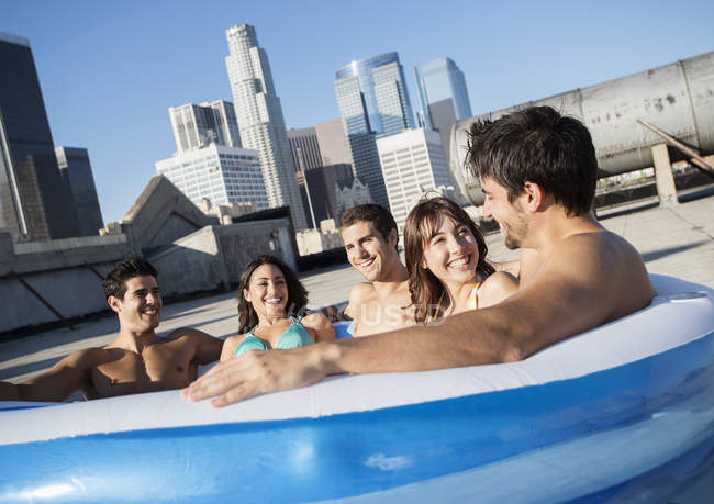 Amigos na piscina inflável em um telhado da cidade — Fotografia de Stock