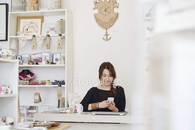 Женщина сидит за столом с помощью смартфона — стоковое фото