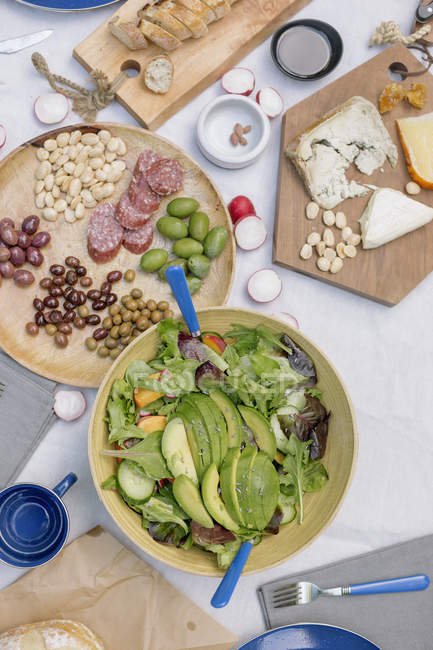 Cheese board and bowl of salad — Stock Photo