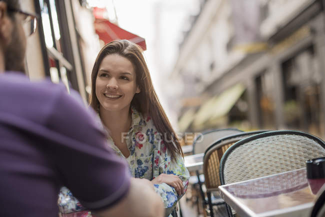 Couple seated on the pavement at a cafe. — Stock Photo