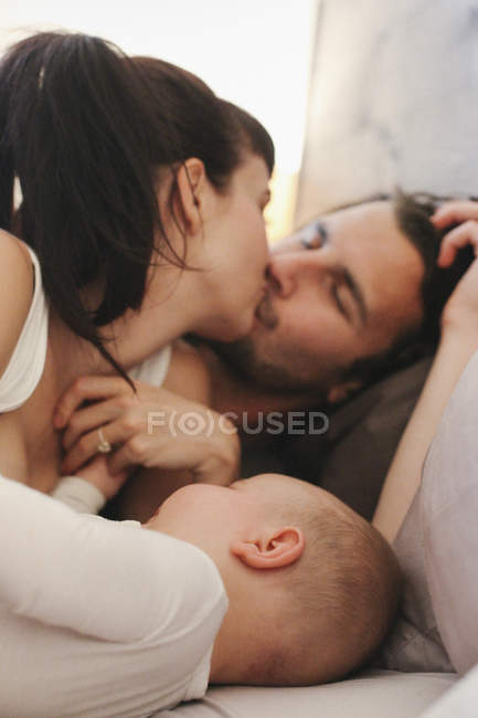 Pais com seu bebê na cama — Fotografia de Stock