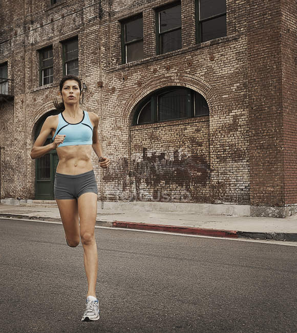Woman running along an urban road — Stock Photo