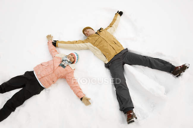 Gente haciendo formas de ángel de nieve . - foto de stock