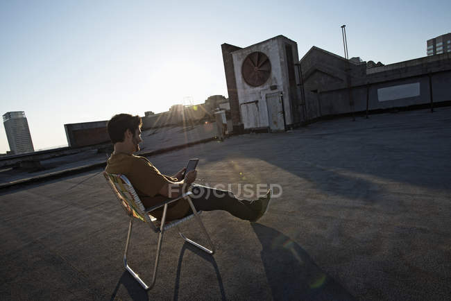 Uomo seduto su una sedia a sdraio sul tetto — Foto stock