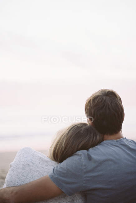 Homme et femme assis sur une plage — Photo de stock