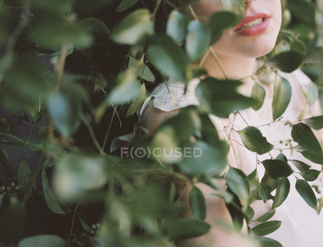 Woman against a wall with a growing vine. — Stock Photo