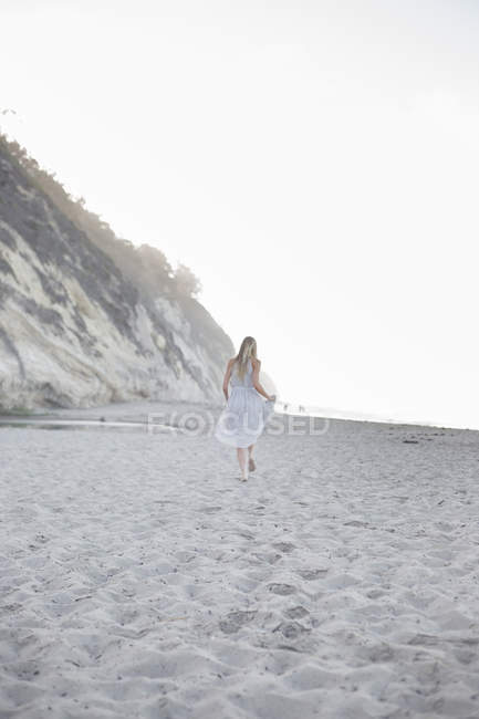 Mujer caminando en una playa de arena - foto de stock