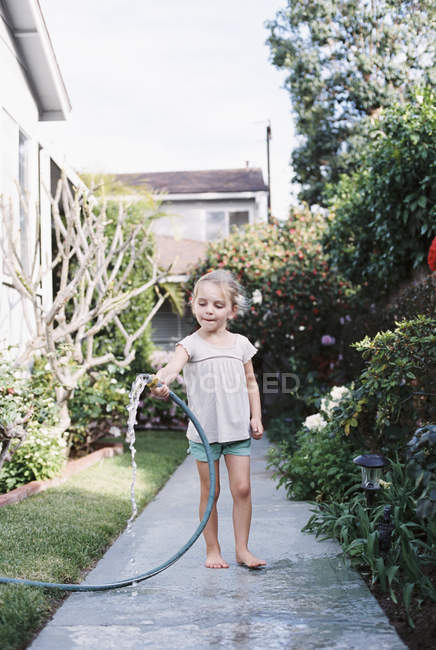 Chica de pie en un camino en un jardín - foto de stock