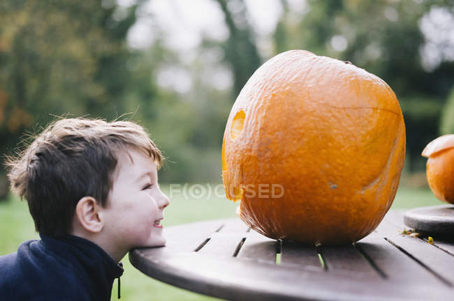Маленький мальчик смотрит на большую тыкву — стоковое фото