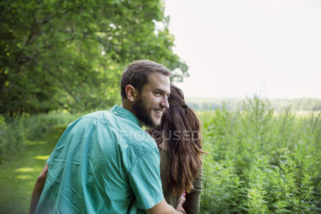 Homem e mulher caminhando através de um prado — Fotografia de Stock